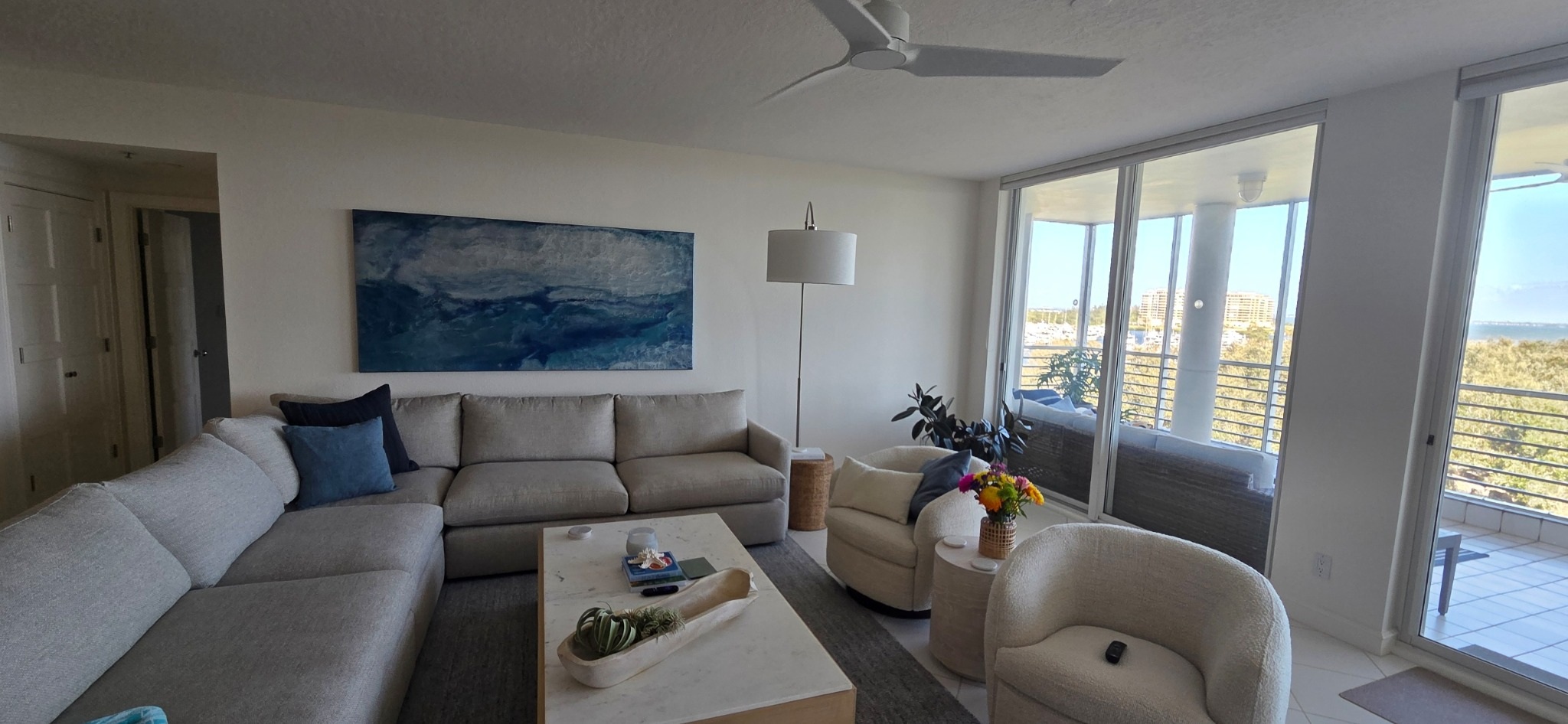 Coastal condo living room with blue artwork above a cream sectional